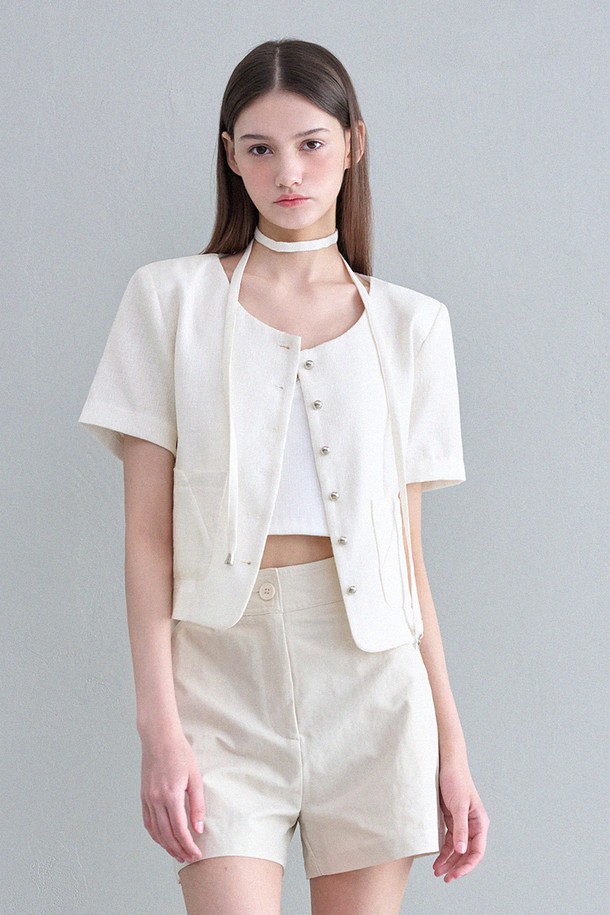 세련된 무드의 여성용 트위드 자켓입니다. 와이드 라운드넥 디자인과 실버 펜던트 장식이 돋보이는 타이 세트가 특징이며, 크롭 기장과 반소매 디자인으로 트렌디함을 더했습니다. 앞 포켓의 시그니처 절개와 트임, 실버 버튼 디테일이 고급스러운 폴리에스테르 소재의 촉감을 더욱 돋보이게 하며 봄, 가을 일상룩에 클래식하면서도 엘레강스한 분위기를 연출합니다.
