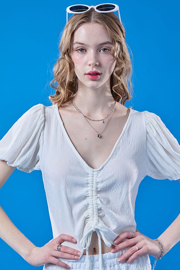 여성스러운 무드를 연출하는 화이트 컬러의 쿨링 플리츠 리본 퍼프 크롭 반팔 티셔츠입니다. 브이넥 디자인에 플리츠, 리본, 퍼프 소매 디테일이 돋보이며, 냉감 기능이 있는 얇은 소재로 여름철에도 시원하게 착용 가능합니다. 크롭 기장으로 스타일리시하게 연출할 수 있습니다.
