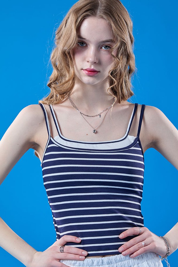 네이비 컬러의 여성용 이너 멀티 나시입니다. 걸리시하고 프레피한 스타일을 연출하며, 여름철 데일리룩에 활용하기 좋습니다. 시원한 민소매 크롭 기장과 스퀘어넥 디자인, 빈티지 스트라이프 패턴이 특징이며, 휴가룩이나 페스티벌 룩으로도 활용할 수 있습니다.
