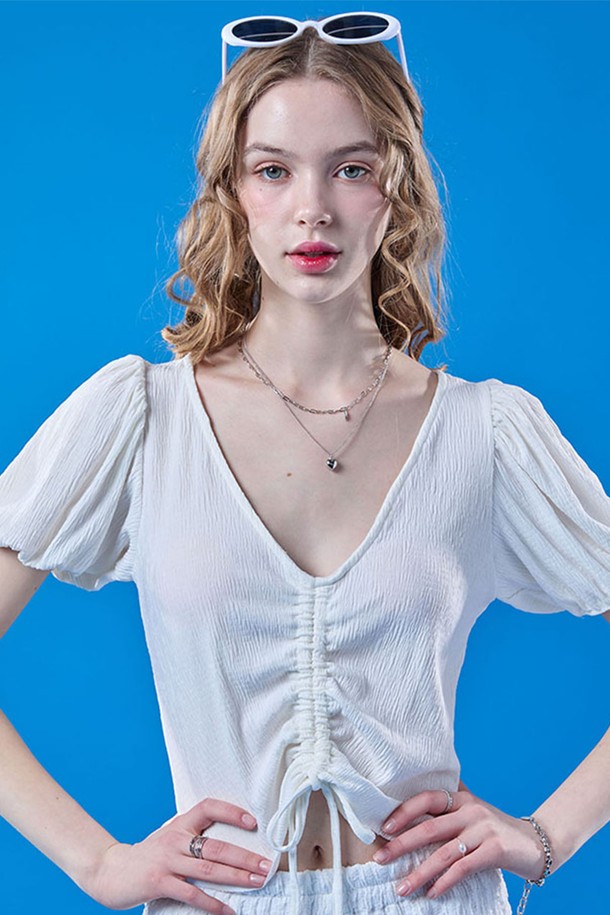 여성스러운 무드를 연출하는 화이트 컬러의 쿨링 플리츠 리본 퍼프 크롭 반팔 티셔츠입니다. 브이넥 디자인에 플리츠, 리본, 퍼프 소매 디테일이 돋보이며, 냉감 기능이 있는 얇은 소재로 여름철에도 시원하게 착용 가능합니다. 크롭 기장으로 스타일리시하게 연출할 수 있습니다.
