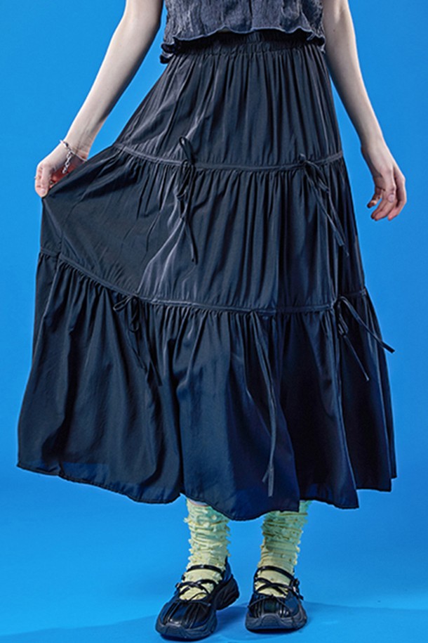 쿨링 기능성 원단으로 제작된 블랙 색상의 롱스커트입니다. 밴딩, 리본, 주름 디테일이 특징이며, 플레어 및 티어드 치마핏으로 페스티벌이나 프레피 스타일을 연출하기에 좋습니다. 여름철 일상에서 시원하고 쾌적하게 착용 가능한 얇은 두께의 롱 플레어스커트입니다.
