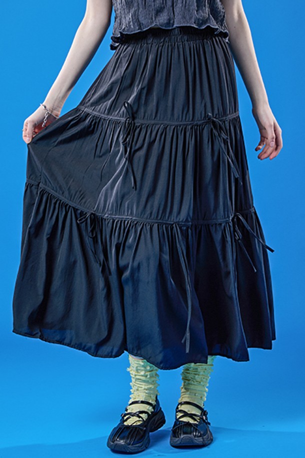 쿨링 기능성 원단으로 제작된 블랙 색상의 롱스커트입니다. 밴딩, 리본, 주름 디테일이 특징이며, 플레어 및 티어드 치마핏으로 페스티벌이나 프레피 스타일을 연출하기에 좋습니다. 여름철 일상에서 시원하고 쾌적하게 착용 가능한 얇은 두께의 롱 플레어스커트입니다.
