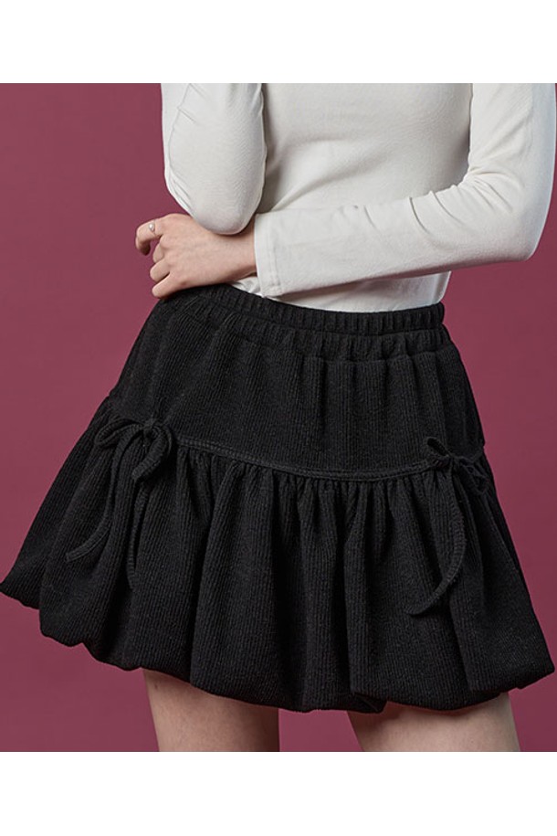 **방한 니트 벌룬 리본 플레어 밴딩 미니스커트 [BLACK] 치마바지 ver.**

따뜻한 겨울과 가을을 위한 여성용 미니스커트입니다. 부드러운 니트 소재로 제작되어 포근한 착용감을 선사하며, 루즈핏 벌룬 디자인과 플레어 스타일로 사랑스러운 분위기를 연출합니다. 허리 밴딩과 리본 디테일이 편안함과 여성스러움을 더하고, 블랙 컬러는 어떤 상의와도 쉽게 매치할 수 있어 활용도가 높습니다. 캐주얼, 미니멀 스타일을 즐겨 입는 분들께 추천하는 아이템입니다.
