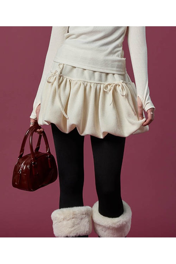 포근한 니트 소재의 방한 미니스커트입니다. 아이보리 컬러의 부드러운 촉감이 특징이며, 벌룬 플레어 디자인과 리본 장식으로 사랑스러운 분위기를 연출합니다. 허리 밴딩 처리로 편안한 착용감을 제공하며, 활동성을 높인 치마바지 스타일로 제작되었습니다. 겨울과 가을 시즌, 캐주얼룩에 따뜻함과 스타일을 더해줄 아이템입니다.

