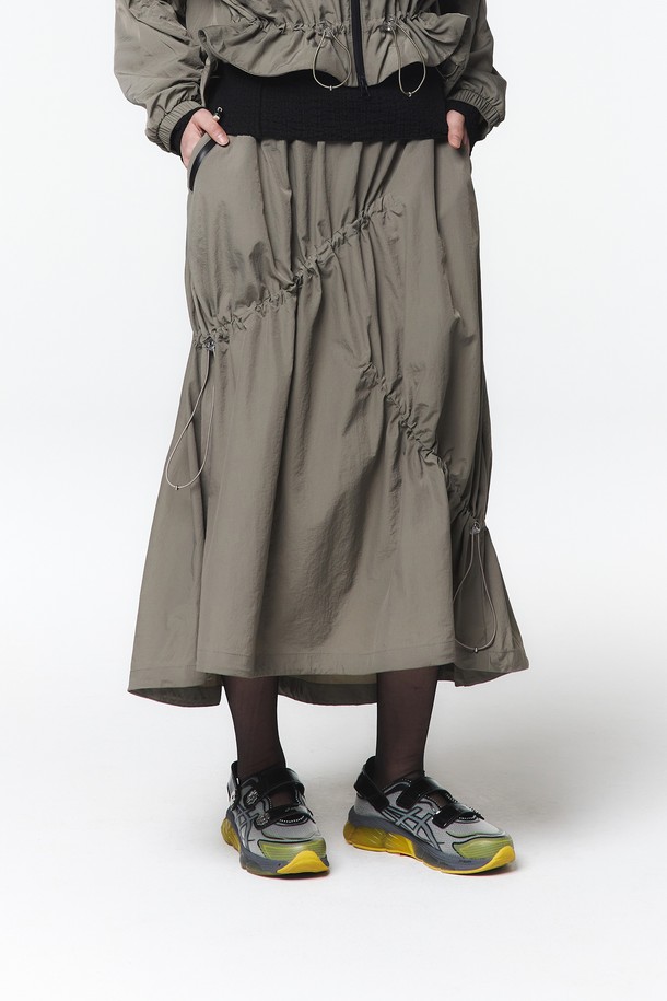 여성용 후디 점퍼와 스커트 셋업(5LB1811)으로, 웜그레이 색상의 캐주얼한 스타일입니다. 하이덴시티 나일론 원단으로 제작되었으며, A라인 플리츠 스커트는 밴딩 허리와 비대칭 스트링 터널, 더블 포켓 디테일이 특징입니다. 사이즈 조절 기능이 있는 루즈핏 디자인으로 봄, 가을에 일상복으로 편안하게 착용할 수 있습니다.
