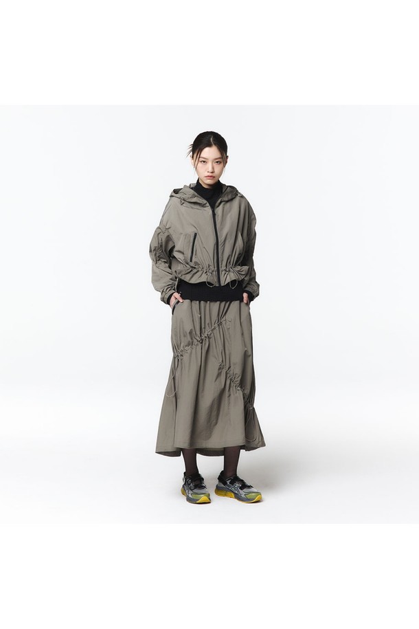 여성용 후디 점퍼와 스커트 셋업(5LB1811)으로, 웜그레이 색상의 캐주얼한 스타일입니다. 하이덴시티 나일론 원단으로 제작되었으며, A라인 플리츠 스커트는 밴딩 허리와 비대칭 스트링 터널, 더블 포켓 디테일이 특징입니다. 사이즈 조절 기능이 있는 루즈핏 디자인으로 봄, 가을에 일상복으로 편안하게 착용할 수 있습니다.
