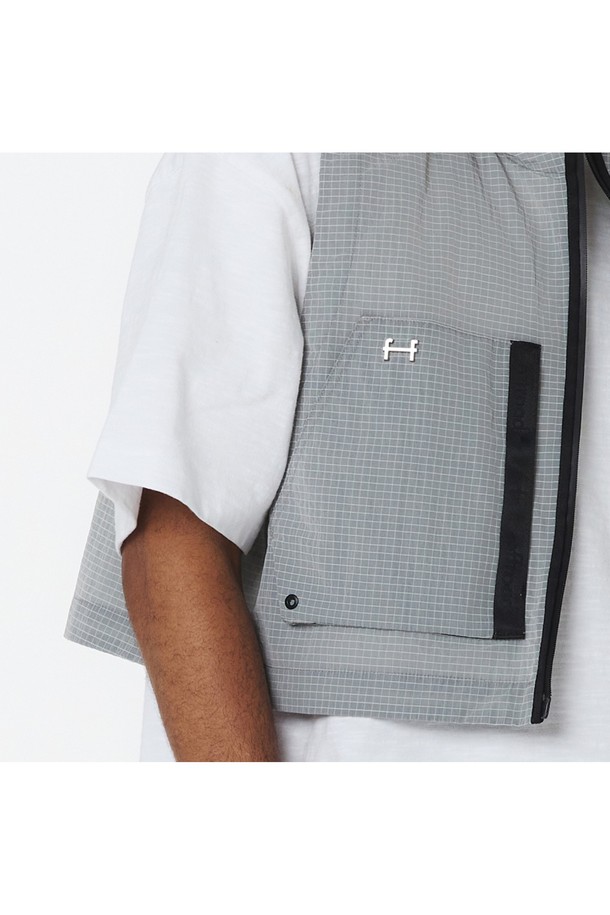 유니 후디 베스트 - RIB (화이트 그레이)_5LG1412는 봄, 가을 시즌에 활용하기 좋은, 얇은 두께의 오버핏 민소매 베스트입니다. 나일론 소재의 립(RIB) 패턴으로 스포티하면서도 캐주얼한 무드를 연출하며, 방풍 및 발수 기능을 갖춰 아웃도어 활동에도 적합합니다. 2WAY 무광 방수 지퍼, 사이드 입체 포켓, 블랙 웨빙 테이프, 반광 FF 금속 장식, 뒷면 로고 자수 등의 디테일이 돋보입니다.
