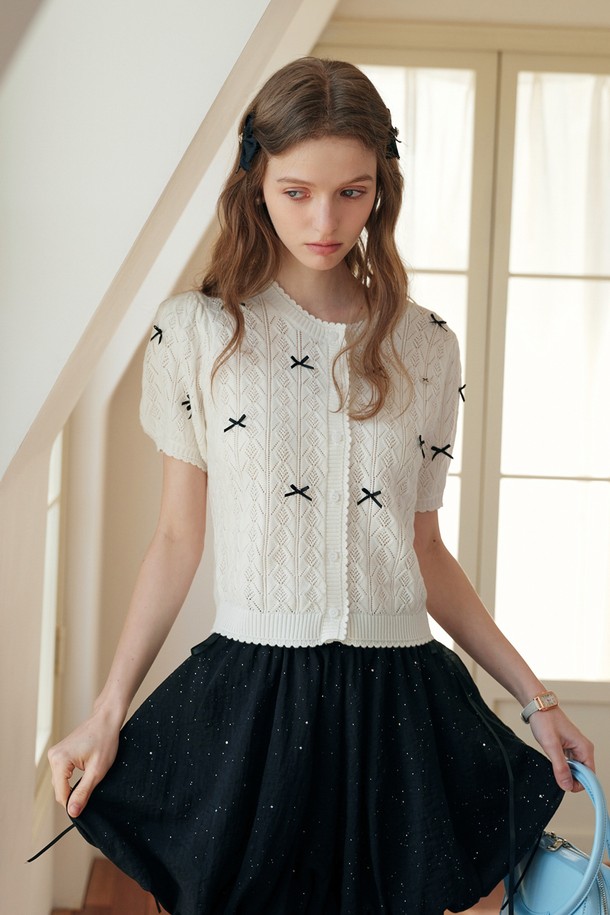 부드러운 촉감의 화이트 컬러 크로셰 리본 반팔 크롭 가디건입니다. 폴리에스테르, 울, 나일론 혼방 소재로 봄, 여름 시즌에 적합하며, 케이블 패턴의 니트 짜임 디테일이 돋보입니다. 라운드 넥과 레귤러 핏, 리본 장식으로 우아하고 캐주얼한 스타일을 연출하며, 리본은 고정되어 있어 편안하게 착용할 수 있습니다.
