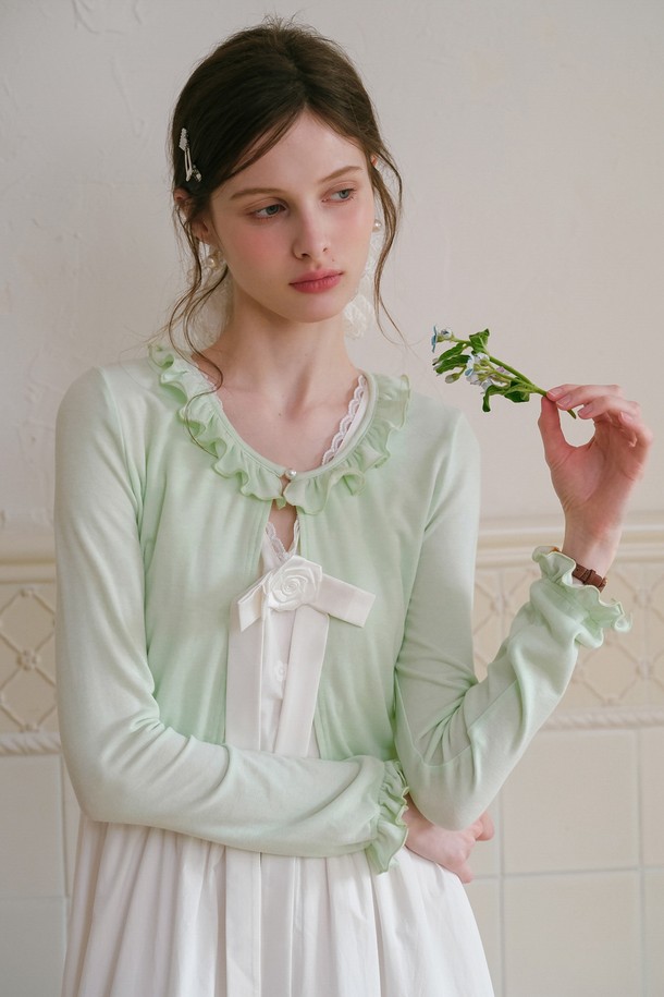 산뜻한 민트 컬러의 프릴 크롭 가디건입니다. 면, 모달, 스판덱스 혼방 소재로 제작되어 부드러운 촉감과 편안한 착용감을 선사하며, 봄, 여름 시즌에 활용하기 좋습니다. 라운드넥에 긴 소매, 레귤러핏으로 디자인되었으며, 프릴 디테일과 리본 장식이 우아한 스타일을 더합니다.
