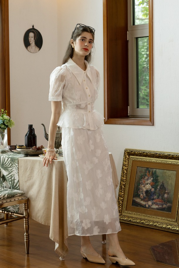 화사한 화이트 컬러의 Grace 패턴 탑 & 스커트 세트입니다. 부드러운 폴리에스테르 소재로 제작되어 봄, 여름 시즌에 시원하게 착용하기 좋으며, A라인 플레어 스커트가 우아한 실루엣을 연출합니다. 라운드넥 반소매 디자인에 허리 밴딩과 스커트 옆지퍼 디테일로 편안함과 활동성을 더했습니다.
