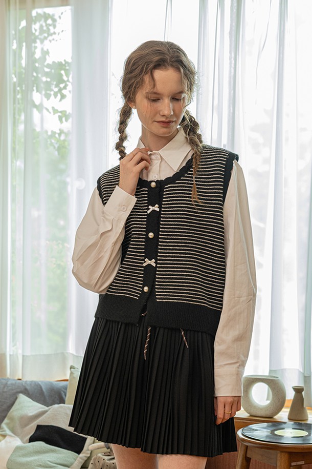 스트라이프 펄 버튼 니트 베스트_2color는 여성스러운 무드를 연출하는 니트 베스트입니다. 부드러운 촉감의 아크릴, 폴리에스테르, 나일론, 울 혼방 소재로 제작되었으며, 봄, 가을 시즌에 착용하기 좋습니다. 라운드넥과 민소매 디자인으로 클래식하고 베이직한 스타일을 연출하며, 크롭 기장과 레귤러핏으로 편안하게 착용 가능합니다. 블랙, 화이트 두 가지 색상으로 제공되며, 진주 버튼과 플리츠 디테일이 포인트로 더해져 데이트룩, 카페룩, 모임룩 등 다양한 TPO에 활용할 수 있습니다. 미니멀, 걸리시 스타일을 선호하는 분들께 추천합니다.
