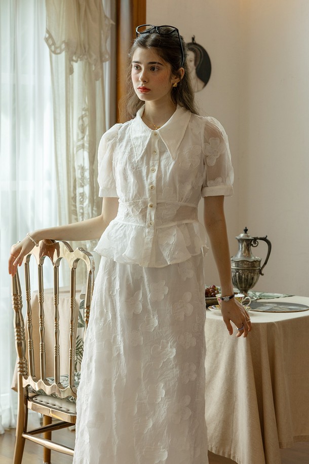 화사한 화이트 컬러의 Grace 패턴 탑 & 스커트 세트입니다. 부드러운 폴리에스테르 소재로 제작되어 봄, 여름 시즌에 시원하게 착용하기 좋으며, A라인 플레어 스커트가 우아한 실루엣을 연출합니다. 라운드넥 반소매 디자인에 허리 밴딩과 스커트 옆지퍼 디테일로 편안함과 활동성을 더했습니다.
