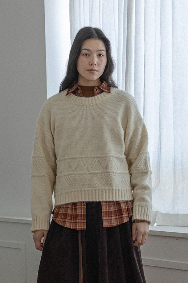 아이보리 컬러의 플리츠 솔리드 컬러 니트 탑입니다. 부드러운 촉감의 울과 아크릴 혼방 소재로 제작되어 가을, 겨울 시즌에 따뜻하게 착용하기 좋습니다. 루즈핏과 라운드넥 디자인으로 편안한 착용감을 선사하며, 긴 소매 기장과 두꺼운 두께감으로 보온성을 높였습니다. 베이직하고 캐주얼한 스타일로 다양한 룩에 활용하기 좋으며, 플리츠 디테일이 포인트로 더해져 세련된 느낌을 줍니다. 니트 특유의 케이블 무늬가 은은하게 드러나 클래식하면서도 미니멀한 분위기를 연출합니다.
