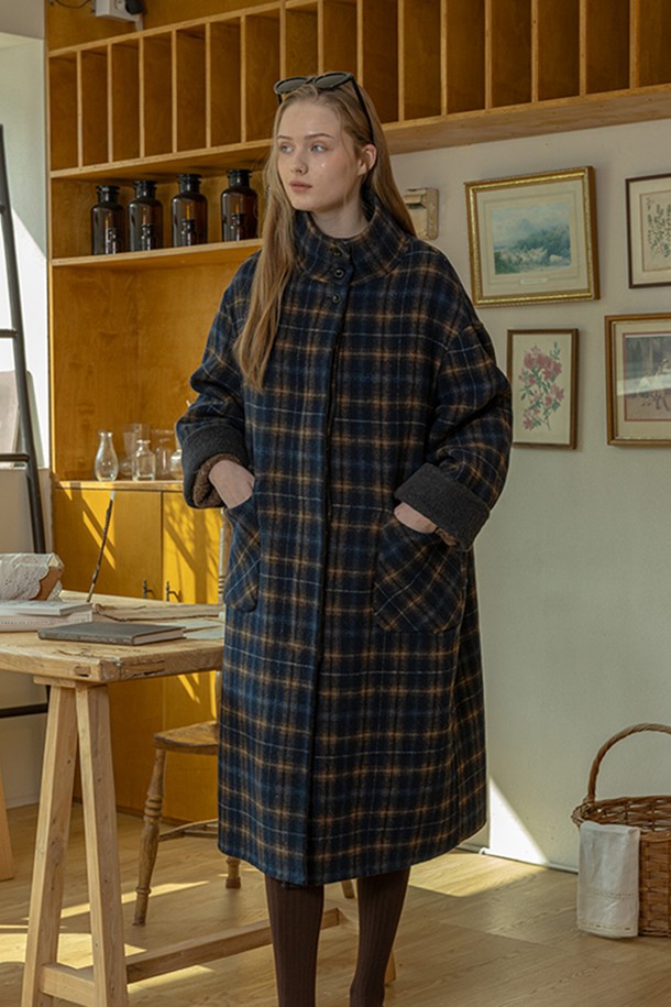 네이비 컬러의 윈터 체크 코트입니다. 울 소재로 제작되어 부드러운 촉감과 두꺼운 두께로 뛰어난 보온성을 제공합니다. 롱 기장의 루즈핏 싱글코트로, 클래식과 캐주얼 스타일 모두 소화 가능하며, 출근룩과 모임룩에 적합합니다. 체크 패턴이 돋보이며, 긴 소매와 버튼 여밈, 그리고 포켓 디테일이 특징입니다. 미니멀한 스타일 연출에도 용이합니다.
