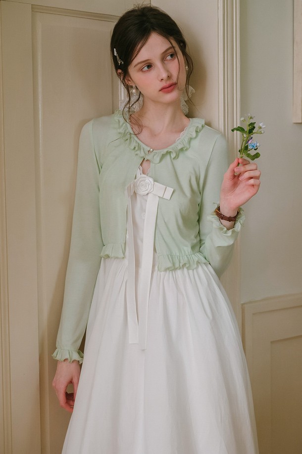 산뜻한 민트 컬러의 프릴 크롭 가디건입니다. 면, 모달, 스판덱스 혼방 소재로 제작되어 부드러운 촉감과 편안한 착용감을 선사하며, 봄, 여름 시즌에 활용하기 좋습니다. 라운드넥에 긴 소매, 레귤러핏으로 디자인되었으며, 프릴 디테일과 리본 장식이 우아한 스타일을 더합니다.
