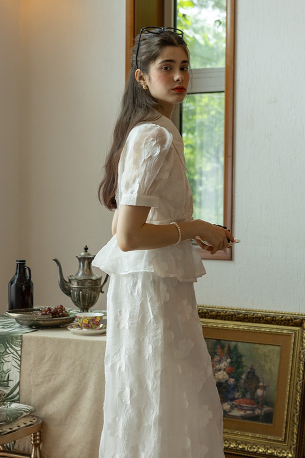 화사한 화이트 컬러의 Grace 패턴 탑 & 스커트 세트입니다. 부드러운 폴리에스테르 소재로 제작되어 봄, 여름 시즌에 시원하게 착용하기 좋으며, A라인 플레어 스커트가 우아한 실루엣을 연출합니다. 라운드넥 반소매 디자인에 허리 밴딩과 스커트 옆지퍼 디테일로 편안함과 활동성을 더했습니다.
