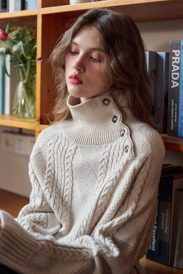 플래킷 터틀넥 케이블 니트는 여성용 상의로, 가을과 겨울에 따뜻하게 착용하기 좋은 두꺼운 두께감의 니트/스웨터입니다. 아이보리와 베이지 두 가지 색상으로 출시되었으며, 베이직하고 클래식한 스타일을 연출합니다. 루즈핏의 크롭 기장으로, 출근룩과 모임룩 모두에 활용 가능하며, 플래킷 디테일이 돋보입니다. 울과 아크릴 혼방 소재의 부드러운 촉감과 케이블 패턴이 특징이며, 민소매 디자인의 터틀넥 스타일로 클래식, 미니멀, 캐주얼 룩에 모두 잘 어울립니다.
