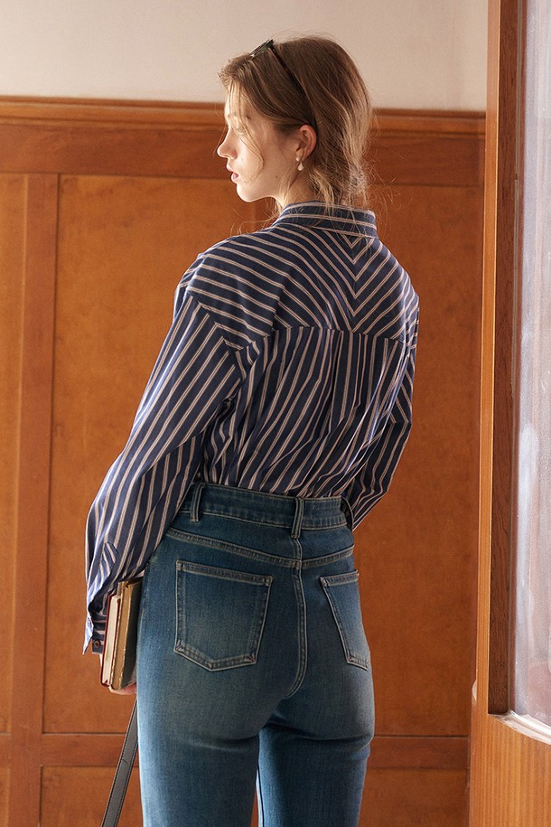 네이비와 화이트 컬러의 스트라이프 패턴이 돋보이는 긴소매 셔츠입니다. 부드러운 면 소재로 제작되어 봄, 가을에 편안하게 착용하기 좋습니다. 차이나 칼라와 루즈핏 디자인으로 베이직하면서도 캐주얼한 스타일을 연출하며, 출근룩 또는 비즈니스 캐주얼에도 활용 가능합니다. 세로 스트라이프 패턴이 시각적인 포인트를 더하며, 버튼다운 디테일로 클래식하고 미니멀한 무드를 더했습니다.
