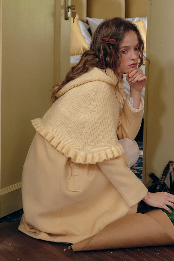 부드러운 니트 소재의 후드 숄입니다. 아이보리 컬러의 이 숄은 가을, 겨울 시즌에 따뜻함과 우아함을 더해줍니다. 클래식하고 우아한 스타일을 연출하며, 케이블 패턴과 프릴 디테일이 돋보입니다. 두꺼운 두께감으로 포근하게 감싸주며, 미니멀한 룩에 포인트 아이템으로 활용하기 좋습니다. 
