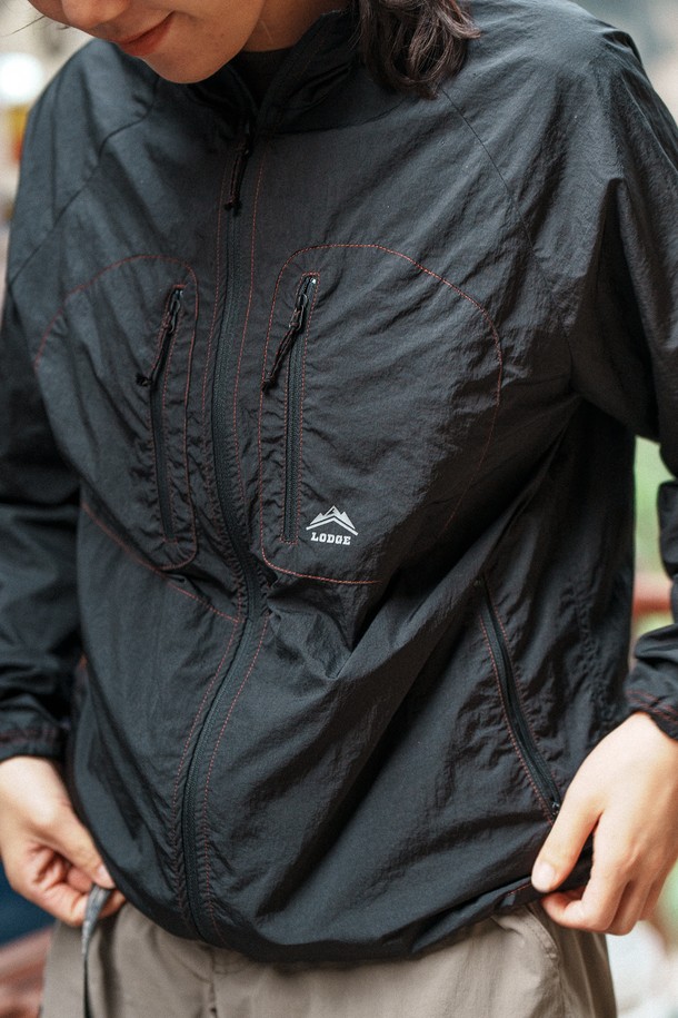 메탈블랙 컬러의 리기 윈드자켓은 남녀 공용으로 하이킹, 캠핑, 일상에서 폭넓게 활용 가능한 아우터입니다. 가볍고 얇은 두께의 나일론 소재로 제작되어 봄, 여름, 가을 간절기에 적합하며, 생활 방수 기능과 180g의 경량 설계로 편안한 착용감을 제공합니다. 후드 일체형 디자인, 입체 패턴 가슴 포켓, 반사 로고, 카라비너 고리 등의 디테일이 돋보이며, 레귤러핏에 집업 스타일로 스포티하고 캐주얼한 스타일을 연출합니다.
