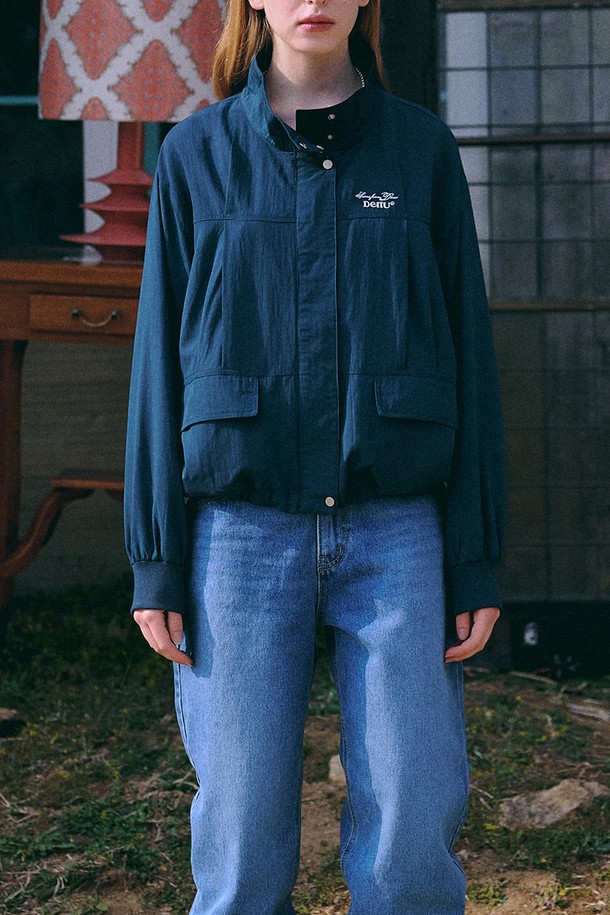 **Scene from Windbreaker [네이비]**는 미니멀하고 베이직한 스타일의 남녀 공용 윈드브레이커입니다. 봄, 가을 시즌에 적합하며, 가볍고 부드러운 레이온, 나일론 혼방 소재로 제작되어 편안한 착용감을 선사합니다. 하이넥 디자인과 가슴 로고 자수 디테일이 특징이며, 대각선 포켓과 밑단 스트링으로 실용성을 더했습니다. 오버핏과 루즈핏으로 연출되어 동네 마실룩, 산책룩, 여행룩 등 다양한 TPO에 활용하기 좋습니다. 얇고 가벼운 두께감으로 방풍 기능까지 갖춘 실용적인 아이템입니다.
