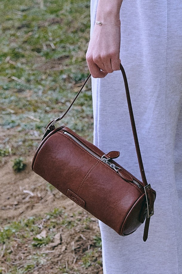 Winsome(윈썸) 배럴 백 [브라운]은 미니멀하고 클래식한 스타일을 선호하는 여성 고객을 위한 가방입니다. 인조 가죽과 합성 가죽 소재로 제작되었으며, 미디엄 사이즈에 무지 패턴과 원통형 디자인을 갖추었습니다. 버클과 스터드/찡 장식으로 포인트를 더했으며, 더블 벨트 스트랩과 조절 가능한 스트랩으로 실용성을 높였습니다. 이중 지퍼와 숨겨진 원형 스터드 장식, 메탈 하드웨어, 빈티지 및 글로스 라인 디테일이 특징이며, 데이트룩, 모임룩 등 일상에서 폭넓게 활용 가능합니다.
