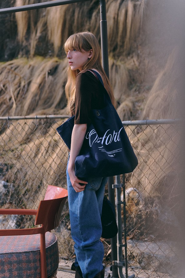 옥스포드 캐주얼 백 [2color]은 아이보리, 네이비 두 가지 색상으로 출시된 여성용 캐주얼 백입니다. 면과 옥스포드 소재를 사용하여 제작되었으며, 미디엄 사이즈의 사각 가방입니다. 가방 전면에 로고와 타이포그래피 패턴이 적용되었고, 28mm 일본산 수제작 버튼으로 포인트를 더했습니다. 넉넉한 수납공간과 편안한 어깨끈, 클래식한 무드로 일상 및 쇼핑룩에 활용하기 좋으며, 아이패드와 맥북 수납이 가능합니다. 빈티지 및 글로시 라인 디자인으로 출시되었습니다.
