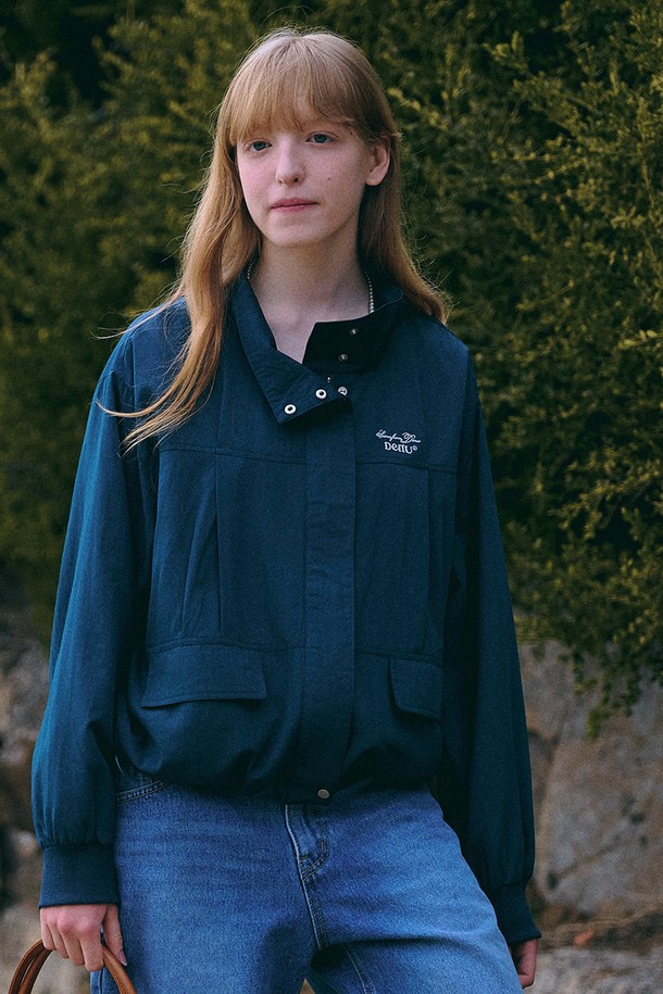 **Scene from Windbreaker [네이비]**는 미니멀하고 베이직한 스타일의 남녀 공용 윈드브레이커입니다. 봄, 가을 시즌에 적합하며, 가볍고 부드러운 레이온, 나일론 혼방 소재로 제작되어 편안한 착용감을 선사합니다. 하이넥 디자인과 가슴 로고 자수 디테일이 특징이며, 대각선 포켓과 밑단 스트링으로 실용성을 더했습니다. 오버핏과 루즈핏으로 연출되어 동네 마실룩, 산책룩, 여행룩 등 다양한 TPO에 활용하기 좋습니다. 얇고 가벼운 두께감으로 방풍 기능까지 갖춘 실용적인 아이템입니다.
