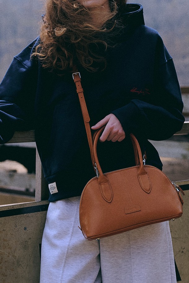 엘렌 시티 토트백 [글로시 카멜]은 부드러운 곡선 실루엣과 돔 쉐이프 디자인이 돋보이는 미디엄 사이즈의 토트백입니다. 광택감 있는 인조가죽 소재에 깔끔한 스티치 디테일이 더해져 클래식하고 베이직한 분위기를 연출합니다. 탈부착 가능한 스트랩과 넉넉한 수납공간, 지퍼형 잠금 방식으로 실용성을 높였으며, 태블릿/노트북 수납도 가능합니다. 데일리룩에 포인트가 되어주는 카멜 컬러와 로고 패치가 시선을 사로잡으며, 다양한 스타일링에 활용하기 좋습니다.
