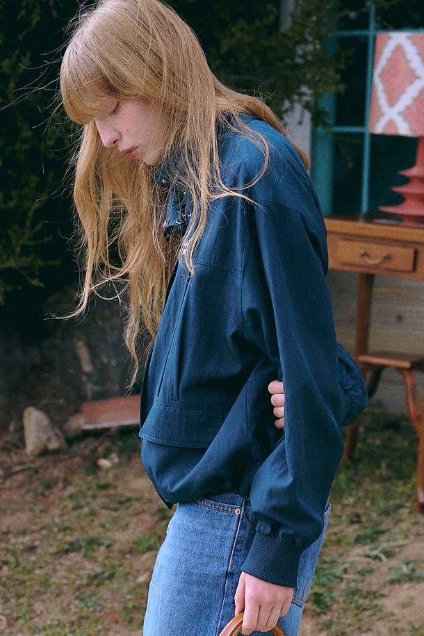 **Scene from Windbreaker [네이비]**는 미니멀하고 베이직한 스타일의 남녀 공용 윈드브레이커입니다. 봄, 가을 시즌에 적합하며, 가볍고 부드러운 레이온, 나일론 혼방 소재로 제작되어 편안한 착용감을 선사합니다. 하이넥 디자인과 가슴 로고 자수 디테일이 특징이며, 대각선 포켓과 밑단 스트링으로 실용성을 더했습니다. 오버핏과 루즈핏으로 연출되어 동네 마실룩, 산책룩, 여행룩 등 다양한 TPO에 활용하기 좋습니다. 얇고 가벼운 두께감으로 방풍 기능까지 갖춘 실용적인 아이템입니다.
