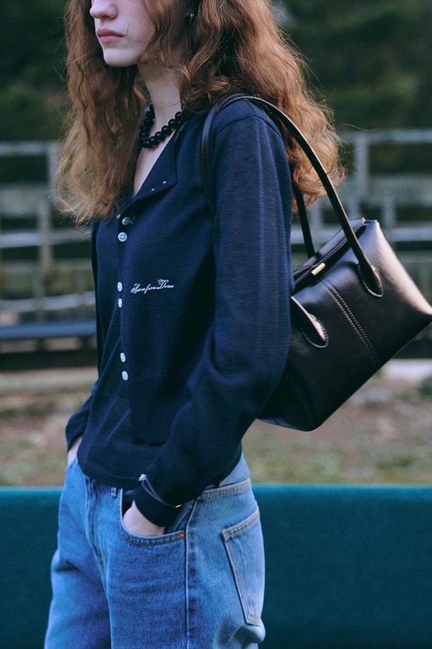 네이비 컬러의 여름 니트 재킷 + 슬리브입니다. 레이온, 린넨, 폴리에스테르 혼방 소재로 제작되어 부드러운 촉감과 하늘거리는 텍스쳐를 자랑합니다. 라운드넥 디자인에 릴렉스 핏으로 편안하게 착용 가능하며, 긴 소매 기장입니다. 시그니처 자수 디테일과 스냅 버튼 클로저가 특징이며, 여름, 간절기에 데이트룩, 카페룩, 캐주얼, 미니멀, 클래식 스타일을 연출하기 좋습니다. 얇은 두께감으로 통기성이 우수하며, 비침이 있을 수 있습니다.
