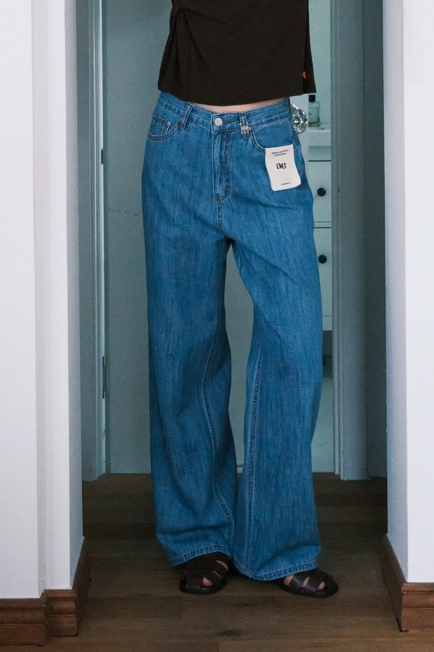 써머 클래식 데님 팬츠_NHDP5260은 여성용 데님 팬츠입니다. 딥블루와 라이트블루 두 가지 색상으로 제공되며, 여름철 일상에서 클래식하고 캐주얼한 스타일을 연출할 수 있습니다. 얇고 부드러운 면과 린넨 혼방 소재로 제작되어 편안한 착용감을 선사하며, 와이드 핏의 긴 기장으로 다리가 길어 보이는 효과를 줍니다. 로고가 각인된 벨트 루프와 탈부착 가능한 캔버스 패널 잠금장치, 면 라벨 디테일이 특징입니다. 데이트룩, 쇼핑룩 등 다양한 상황에 미니멀한 스타일로 활용하기 좋습니다.
