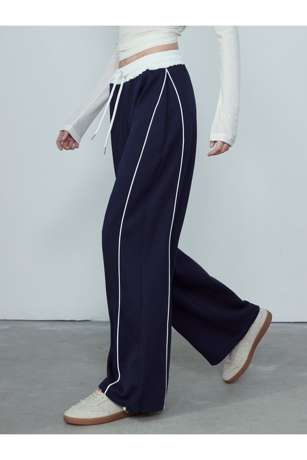 CONTOUR LINE 투웨이 밴딩 와이드 팬츠_NFTR5307는 편안함과 스타일을 동시에 잡은 공용 와이드핏 트레이닝 팬츠입니다. 부드러운 촉감의 폴리에스테르와 면 혼방 소재로 제작되어 사계절 내내 활용 가능하며, 밴딩 허리 디자인으로 편안한 착용감을 제공합니다. 세로 파이핑 라인과 허리 배색 디테일이 스포티한 무드를 더하고, 하단 스토퍼 장식으로 활동성을 높였습니다. 일상, 스포츠 활동은 물론, 동네 마실룩, 피트니스룩, 여행룩 등 다양한 TPO에 맞춰 캐주얼하고 미니멀한 스타일을 연출할 수 있습니다. 
