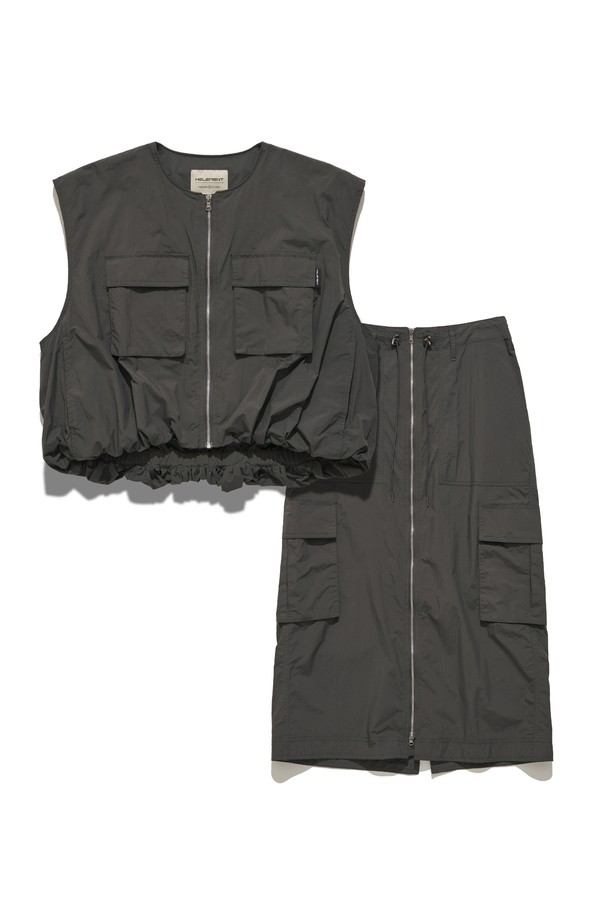 여성용 D GREY 컬러 필드 카고 스커트 SET입니다. 나일론 소재의 H라인 카고스커트와 민소매 베스트가 세트로 구성되어 있으며, 캐주얼하고 스포티한 무드를 연출합니다. 2-WAY 지퍼 디테일, 아웃포켓 디자인, 밑단 개더링 디테일이 돋보이며, 사계절 아웃도어 및 일상에서 활용하기 좋습니다.
