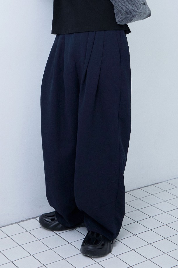 네이비 컬러의 드래프트 스트링 와이드 팬츠입니다. 여름철 시원하게 착용하기 좋은 얇은 두께감의 루즈핏 와이드 팬츠로, 레이온, 폴리에스테르, 나일론 혼방 소재로 제작되어 부드러운 촉감을 선사합니다. 허리 밴딩과 밑단 스트링 디테일이 편안한 착용감을 제공하며, 다트 디테일로 입체적인 실루엣을 완성합니다. 구김이 적고 통기성이 좋아, 동네 마실룩, 여행룩, 캐주얼, 미니멀, 클래식 스타일 등 다양한 스타일에 활용하기 좋습니다.
