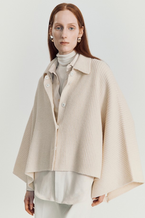 로디 케이프 니트 재킷_ 아이보리는 여성스러운 실루엣과 우아한 분위기를 연출하는 케이프 스타일의 겨울 아우터입니다. 부드러운 울과 나일론 혼방 소재로 제작되어 포근하고, 두꺼운 두께감으로 보온성을 높였습니다. 크롭 기장의 루즈핏으로 편안하게 착용 가능하며, 버튼 여밈 방식으로 간편하게 스타일링할 수 있습니다. 아이보리, 베이지, 브라운, 블랙 등 다채로운 색상으로 출시되어 데이트룩, 겨울 데일리룩, 모임룩 등 폭넓은 TPO에 활용할 수 있습니다. 클래식, 미니멀, 시크한 스타일을 즐기는 여성에게 추천하는 아이템입니다.
