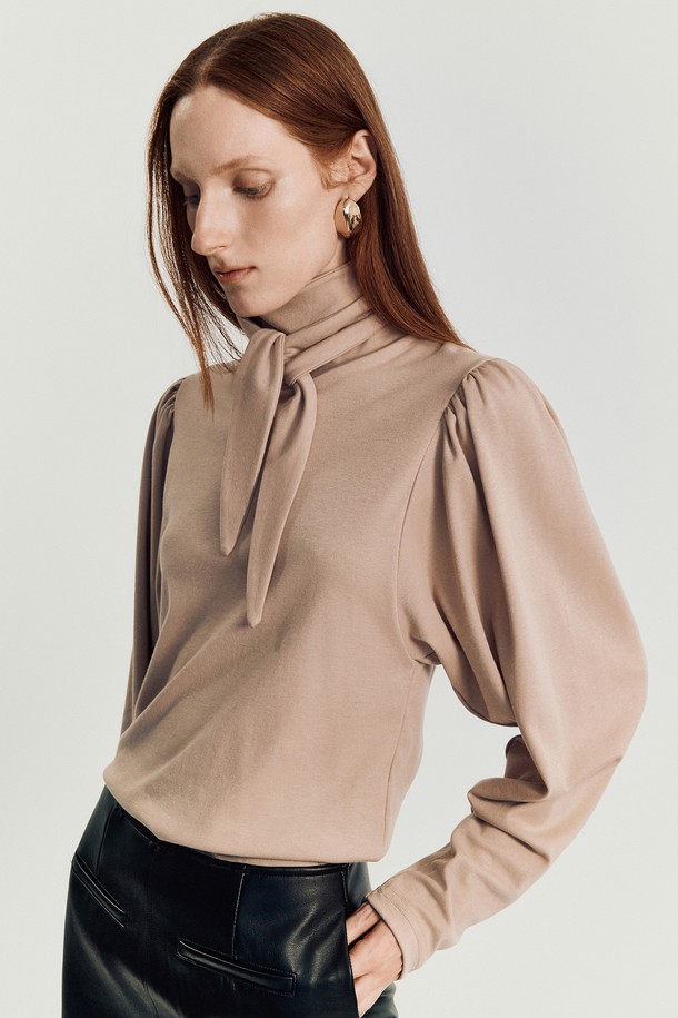 린지 타이 티셔츠 _ 베이지는 여성스러운 무드를 연출하는 슬림핏 긴소매 티셔츠입니다. 부드러운 면과 텐셀 혼방 소재로 제작되어 편안한 착용감을 선사하며, 하이넥 또는 리본 타이로 연출 가능한 넥 라인이 특징입니다. 은은한 베이지 컬러에 퍼프 숄더와 리본 타이 디테일이 더해져 우아하고 미니멀한 스타일을 완성합니다. 데이트룩, 모임룩, 카페룩 등 다양한 TPO에 활용 가능하며, 클래식, 미니멀, 로맨틱 스타일을 즐기는 분들께 추천합니다.
