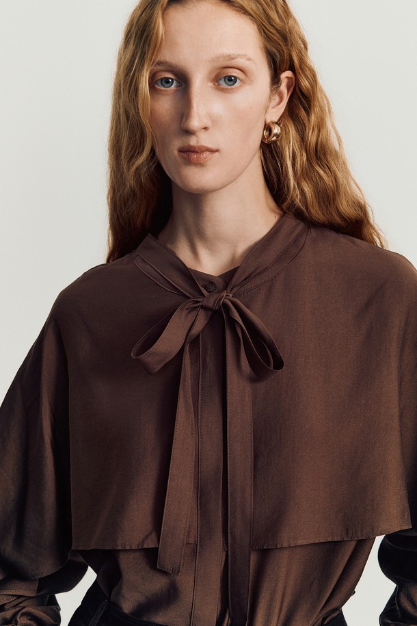 나디 케이프 블라우스 _ 브라운은 여성스러운 무드를 자아내는 블라우스입니다. 봄, 가을에 어울리는 긴소매 디자인으로, 루즈핏의 편안한 착용감을 선사합니다. 부드러운 레이온과 폴리에스테르 혼방 소재로 제작되어 은은한 광택과 고급스러운 촉감을 느낄 수 있습니다. 케이프 디자인과 3D 패턴 디테일, 스텝드 슬리브 플랩, 버튼 플래킷이 더해져 엘레강스하고 우아한 스타일을 완성합니다. 데이트룩, 모임룩, 오피스룩 등 다양한 TPO에 클래식, 미니멀, 로맨틱한 스타일로 연출해보세요.
