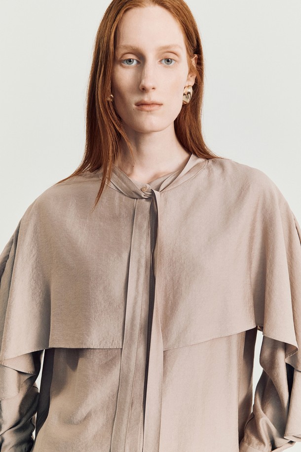 나디 케이프 블라우스 (Pink)는 여성스러운 무드를 연출하는 블라우스입니다. 부드러운 레이온과 폴리에스테르 혼방 소재로 제작되어 봄, 여름에 시원하게 착용하기 좋습니다. 라운드넥에 케이프 디자인과 타이 디테일, 티어드 슬리브가 더해져 우아하고 로맨틱한 스타일을 완성합니다. 루즈핏으로 편안하며, 핑크와 브라운 두 가지 색상으로 출시되어 데이트룩, 카페룩, 모임룩 등 다양한 TPO에 활용할 수 있습니다. 클래식하고 미니멀한 스타일을 선호하는 분들께 추천합니다.
