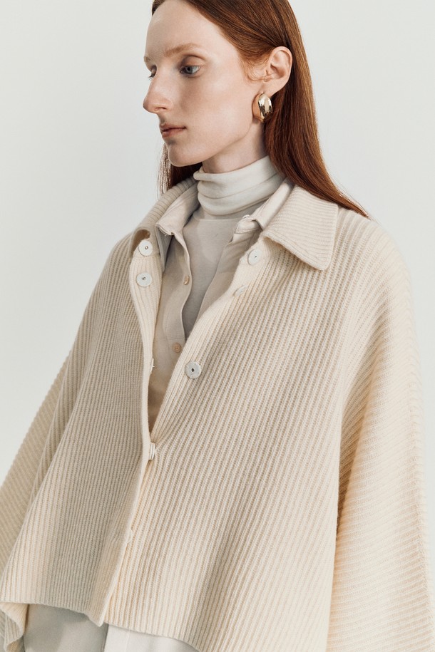 로디 케이프 니트 재킷_ 아이보리는 여성스러운 실루엣과 우아한 분위기를 연출하는 케이프 스타일의 겨울 아우터입니다. 부드러운 울과 나일론 혼방 소재로 제작되어 포근하고, 두꺼운 두께감으로 보온성을 높였습니다. 크롭 기장의 루즈핏으로 편안하게 착용 가능하며, 버튼 여밈 방식으로 간편하게 스타일링할 수 있습니다. 아이보리, 베이지, 브라운, 블랙 등 다채로운 색상으로 출시되어 데이트룩, 겨울 데일리룩, 모임룩 등 폭넓은 TPO에 활용할 수 있습니다. 클래식, 미니멀, 시크한 스타일을 즐기는 여성에게 추천하는 아이템입니다.
