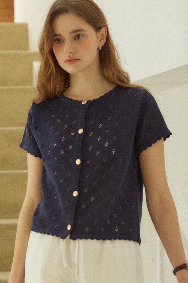 골디쉬 버튼 펀칭 가디건 - 네이비는 여성스러운 무드를 연출하는 봄 시즌 필수 아이템입니다. 부드러운 아크릴 소재와 얇은 두께감으로 편안한 착용감을 선사하며, 라운드넥과 레귤러핏 디자인으로 단정하면서도 여성스러운 실루엣을 완성합니다. 네이비, 아이보리, 레드의 세련된 컬러 팔레트로 다양한 스타일을 연출할 수 있으며, 펀칭 레이스 패턴과 스캘럽 엣지 디테일이 로맨틱한 분위기를 더합니다. 18K 골드 도금 버튼과 골드 로고 디테일이 고급스러움을 더하며, 형태 유지력과 필링 방지 기능으로 오랜 기간 변함없이 착용할 수 있습니다. 데이트룩, 카페룩과 같은 특별한 날이나 데일리룩으로 활용하여 클래식하면서도 사랑스러운 분위기를 연출해 보세요.
