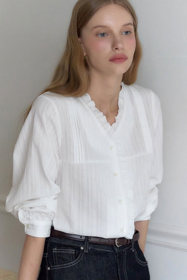 아이보리 색상의 V넥 러플 핀턱 블라우스입니다. 부드러운 면 소재로 제작되어 사계절 내내 편안하게 착용 가능하며, 레귤러 핏으로 여성스러운 실루엣을 연출합니다. 페미닌, 클래식, 프레피 스타일을 모두 아우르는 디자인으로, 데이트룩, 오피스룩, 모임룩 등 다양한 TPO에 활용할 수 있습니다. V넥 라인과 러플, 핀턱 디테일이 여성스러운 무드를 더하며, 프리미엄 자개 로고 버튼으로 고급스러움을 더했습니다. 긴 소매 기장으로 간절기에도 적합하며, 데일리 스타일링에 활용하기 좋습니다.
