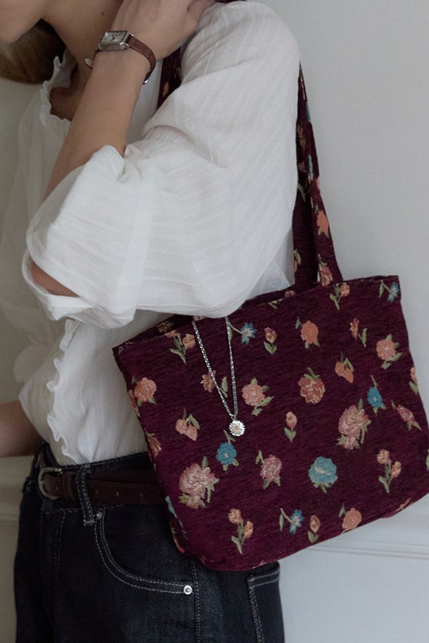 버건디 컬러의 Garnet Jacquard Flower Bag (가넷 자카드 플라워 백)입니다. 플라워 자카드 패턴과 실버 데이지 장식이 돋보이는 여성 가방으로, 미디엄 사이즈의 사각 디자인이 특징입니다. 폴리에스터와 면 혼방 소재로 제작되었으며, 클래식하고 프레피한 스타일을 연출합니다. 가을/겨울 시즌에 어울리는 아이템으로, 내부 라이닝 처리가 되어 있습니다. 일상 속 카페룩, 가을 나들이룩에 매치하여 지갑, 휴대폰, 기본 화장품 등을 수납하기 좋습니다.
