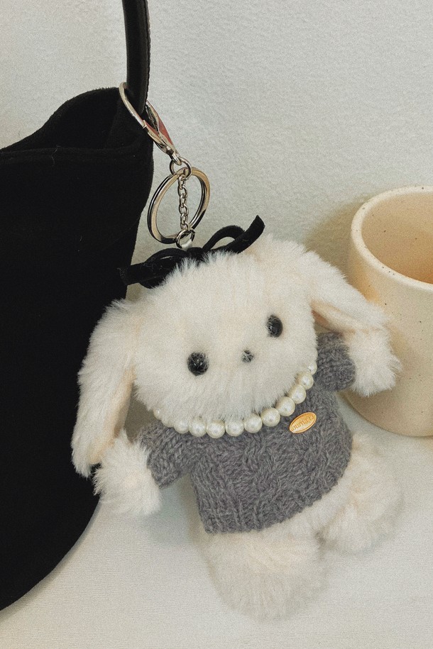 Hoppy The Lucky Rabbit (호피 더 럭키 래빗) 니트 키링 - 화이트는 부드러운 극세사 소재로 제작된 공용 키링입니다. 귀여운 토끼 캐릭터 디자인에 봉제인형 스타일로 제작되어 소장 가치를 높였습니다. 화이트 컬러의 바탕에 그레이 컬러 의상을 착용하고 있으며, 작은 리본 장식이 걸리시한 분위기를 더합니다. 미니 사이즈로 제작되어 가방이나 열쇠에 간편하게 걸어 사용할 수 있으며, 키홀더 기능으로 실용성까지 갖춘 캐주얼 스타일의 제품입니다.