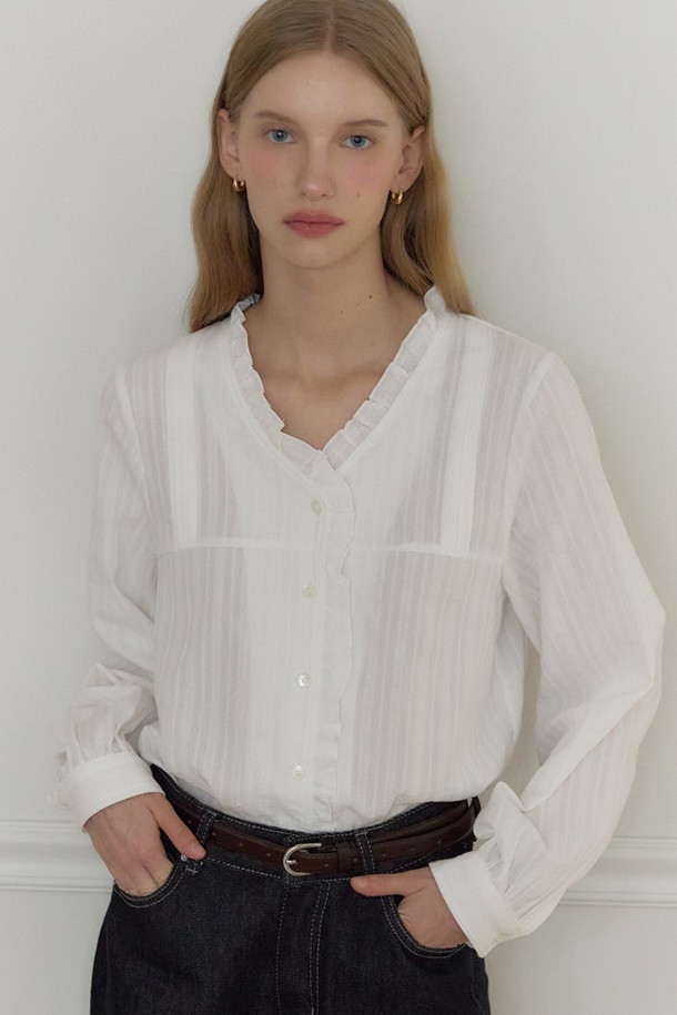 아이보리 색상의 V넥 러플 핀턱 블라우스입니다. 부드러운 면 소재로 제작되어 사계절 내내 편안하게 착용 가능하며, 레귤러 핏으로 여성스러운 실루엣을 연출합니다. 페미닌, 클래식, 프레피 스타일을 모두 아우르는 디자인으로, 데이트룩, 오피스룩, 모임룩 등 다양한 TPO에 활용할 수 있습니다. V넥 라인과 러플, 핀턱 디테일이 여성스러운 무드를 더하며, 프리미엄 자개 로고 버튼으로 고급스러움을 더했습니다. 긴 소매 기장으로 간절기에도 적합하며, 데일리 스타일링에 활용하기 좋습니다.
