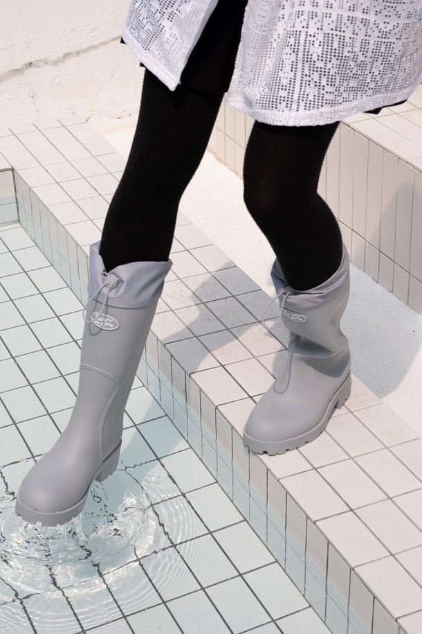 HOU 롱 레인 부츠는 5가지 다채로운 컬러(블랙, 브라운, 그레이, 아이보리, 레몬)로 출시되어 넉넉한 선택지를 제공합니다. 일상과 우천 시 모두 활용 가능한 이 부츠는 5cm 통굽 디자인과 셔링 탑라인으로 캐주얼하면서도 미니멀한 스타일을 연출합니다. 논슬립 아웃솔과 넓은 아웃솔 디자인으로 미끄럼 방지 기능을 갖췄으며, 방수 소재(PVC)와 커프 디테일로 실용성을 더했습니다. 부츠와 함께 더스트백이 포함되어 보관 또한 용이합니다.
