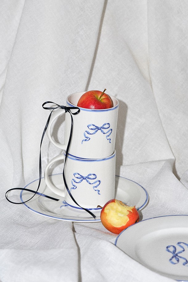 리본블루 머그&접시 1인 세트 2P (베이직)는 파인본차이나 소재로 제작되어 40% 이상 본회분을 함유하여 얇고 가벼우면서도 내구성이 뛰어나 일상에서 편안하게 사용할 수 있습니다. 화이트와 블루 컬러의 조화, 리본 패턴 디자인이 돋보이며, 1250-1300도 고온 소성으로 보온성이 우수하고 반투명 유백색을 띱니다. 본 세트는 머그컵 1개와 원형 접시 1개로 구성되어 전자레인지 및 식기세척기 사용이 가능하며, KS 제품인증, 납/카드뮴 불검출, 잉크침투저항성 0.0, 내열충격성 120도, 24K 골드인증(GBC780B)을 획득하여 안심하고 사용할 수 있습니다.
