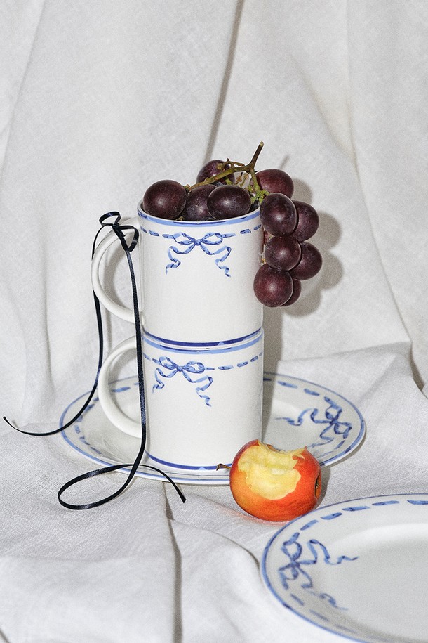 리본블루 머그&접시 1인 세트 2P (스티치)는 파인본차이나 소재로 제작되어 은은한 화이트와 블루 색상의 조화가 돋보입니다. 빈티지하면서도 우아한 리본과 보더 무늬 디자인이 특징이며, 전자레인지 및 식기세척기 사용이 가능하여 실용적입니다. 본애쉬 40% 이상 함유, 얇고 가벼운 무게, 높은 내구성과 보온성으로 편안하고 품격 있는 식사 시간을 선사합니다.
