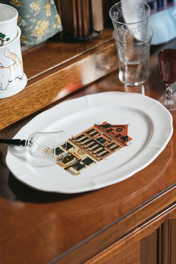 한국도자기 X 티보에렘 (Thibaud Herem)의 46. 오발 접시 28CM 1P (Villa le Lezard)는 섬세한 건축물 일러스트가 돋보이는 본차이나 접시입니다. 28cm 크기의 오발 형태로, 티보에렘 (Thibaud Herem) 작가의 0.1mm 펜과 연필을 사용한 아날로그 방식의 건축물 일러스트를 세라믹 전사 기술로 담아냈습니다. 40% 이상의 본회분 함유로 얇고 가벼우면서도 내구성이 뛰어나며, 120도의 내열성을 지녀 전자레인지 및 식기세척기 사용이 가능합니다. 유백색 투광성과 낮은 흡수율, KS 제품 인증, 납/카드뮴 불검출 시험성적서, 24K 골드 인증으로 품질을 보장합니다. 제품 규격은 가로 21cm, 세로 28cm, 높이 2.2cm이며, 1250-1300°C의 소성온도와 0.0의 잉크 침투율을 자랑합니다.
