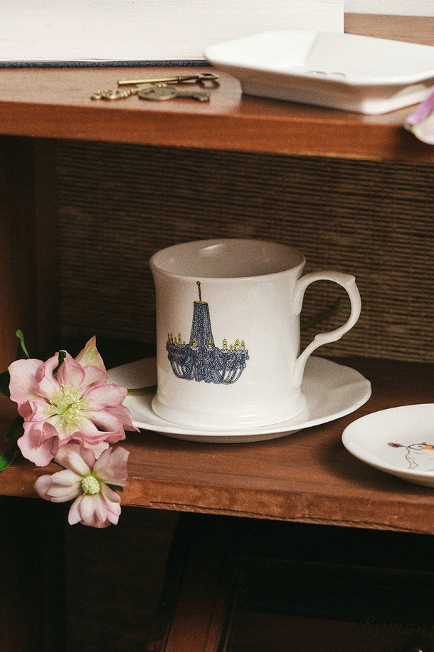 [한국도자기X티보에렘] 07. 머그 1P (크리스탈 샹들리에)는 40% 이상의 본애쉬를 함유한 본차이나 소재의 머그컵입니다. 0.1mm 펜과 연필로 수작업 일러스트를 완성하고, 세라믹 전사 기술을 적용하여 샹들리에 무늬를 섬세하게 표현했습니다. 1250~1300도의 고온 소성으로 제작되어 내열성과 내구성이 뛰어나며, 전자레인지 및 식기세척기 사용이 가능합니다. 24K 골드 인증을 받았으며, 납/카드뮴 불검출 및 잉크 침투율 0.0으로 안전하게 사용할 수 있습니다. 내열 충격 120도로 일상생활에서 편리하게 사용하기 좋습니다.
